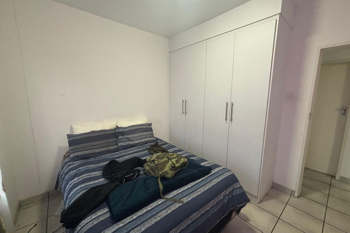 A bedroom featuring built-in white cupboards and tiled flooring, providing functional storage space.