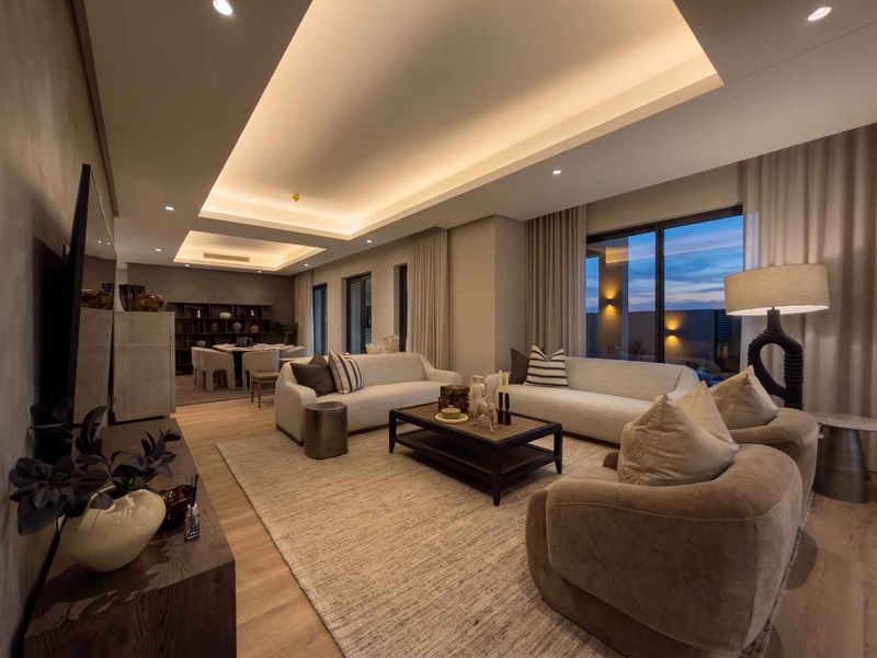 Spacious open-plan living and dining area featuring modern recessed cove lighting, high-quality hardwood flooring, and large sliding glass doors leading to an outdoor space.