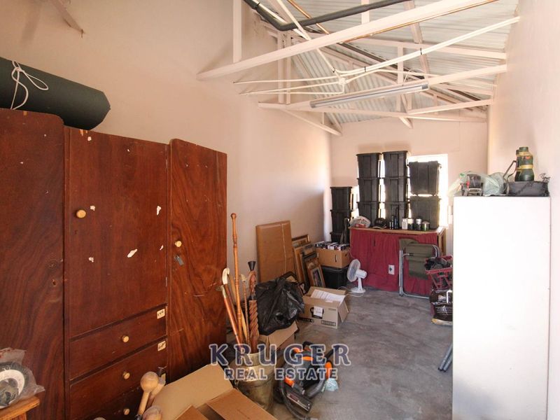 A utility garage space featuring exposed roof trusses and concrete flooring, currently used for storage.