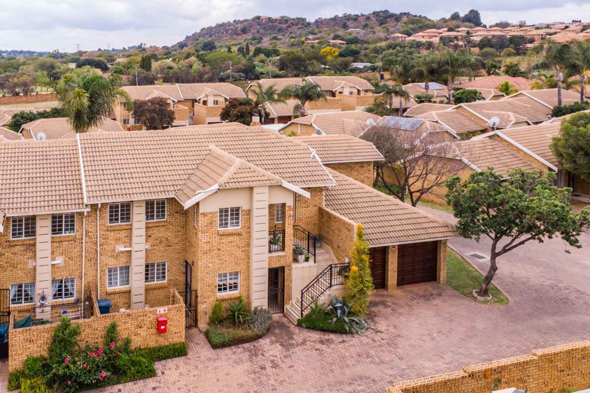 Aerial view of a multi-unit residential apartment complex featuring face-brick facades, tiled roofs, paved driveways, and integrated garage units.