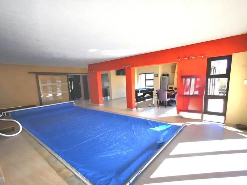 Indoor swimming pool area featuring tiled flooring and direct access to adjacent living spaces through large openings.