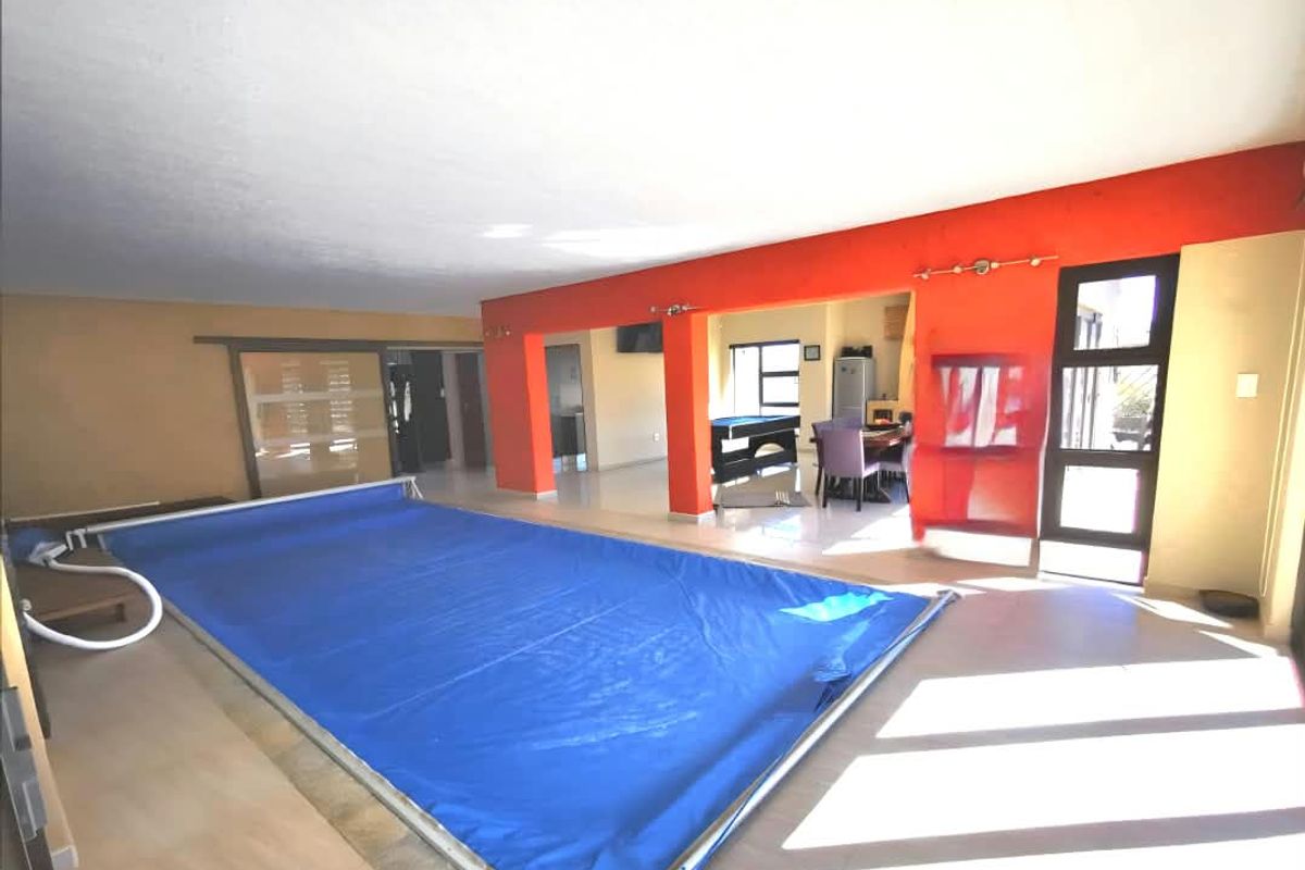 Indoor swimming pool area featuring tiled flooring and direct access to adjacent living spaces through large openings.