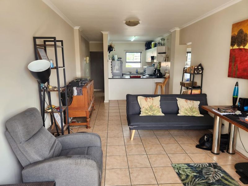Open-plan living area featuring tiled flooring and a functional kitchen with built-in cabinetry and a breakfast counter.