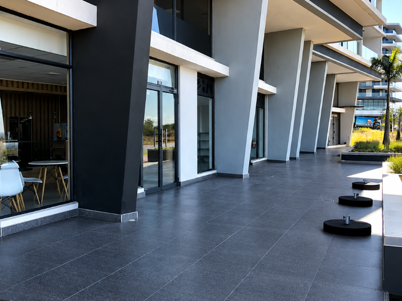 Modern commercial retail storefront featuring large format floor tiles, expansive glass windows, and prominent structural concrete pillars.