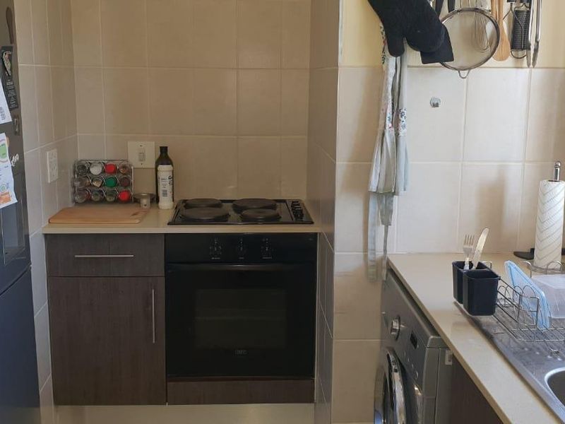 A functional kitchen featuring built-in cabinetry, a stainless steel sink, tiled splashbacks, and integrated oven and hob appliances.