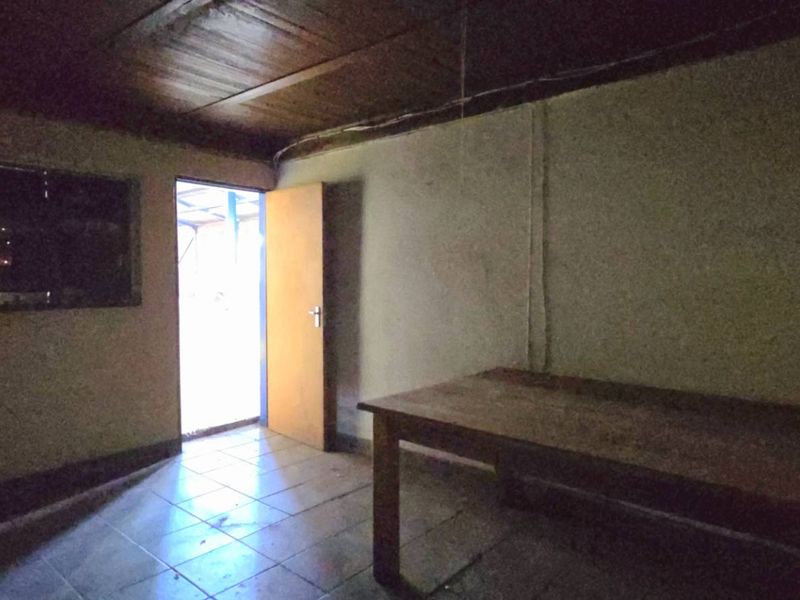 A basic utility space featuring tiled flooring and a timber ceiling, currently vacant and requiring cosmetic refurbishment.