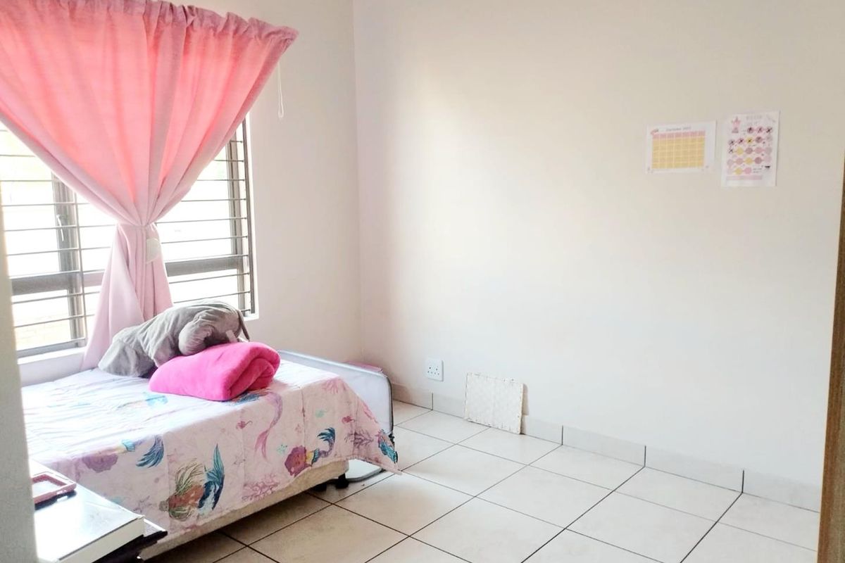 A bedroom featuring tiled flooring, a large window with horizontal blinds, and neutral wall finishes.