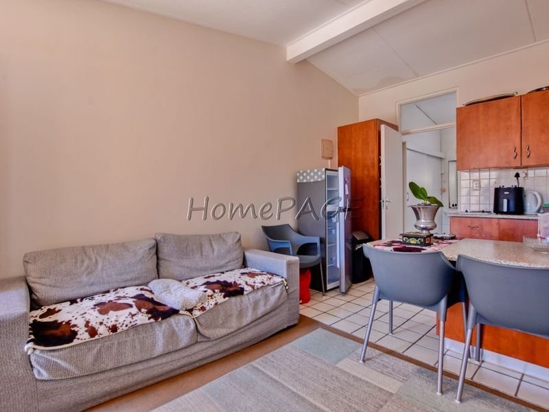 Open plan living and kitchen area featuring tiled flooring, built-in cabinetry, and a tiled backsplash, suitable for modern updates.