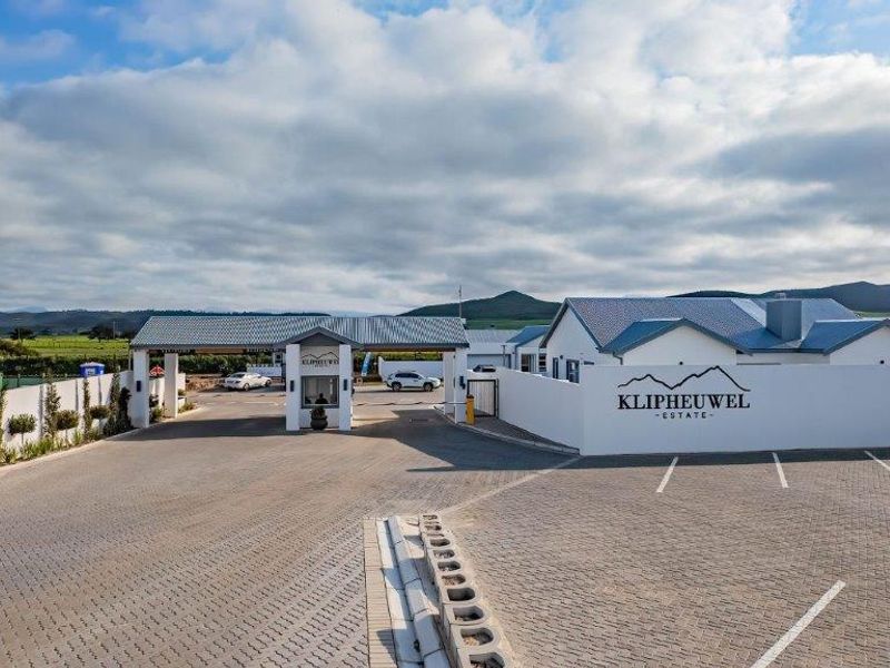 The entrance to Klipheuwel Estate featuring a secure gatehouse, paved driveway, and well-maintained boundary walls with clear estate signage.