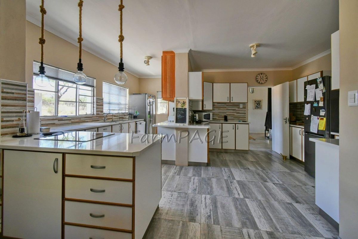 Spacious kitchen featuring a central island, built-in cabinetry, tiled flooring, and ample counter space, offering a functional layout for meal preparation.