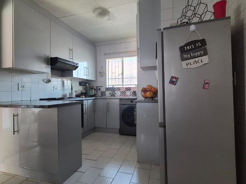 A functional kitchen featuring grey cabinetry, tiled backsplash, built-in oven, extractor fan, and tiled flooring, offering a practical layout for daily meal preparation.