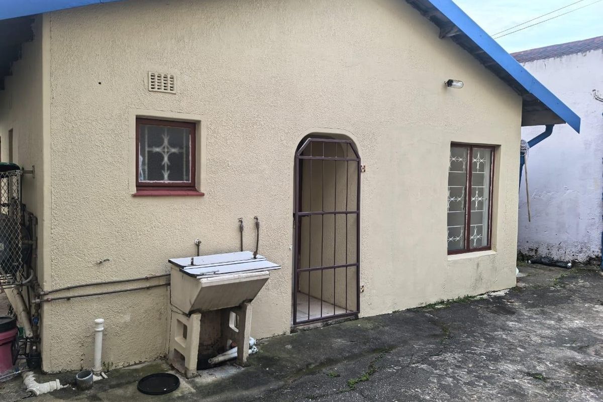Rear exterior view of the property featuring a concrete laundry trough, security gate, and security bars on the windows.