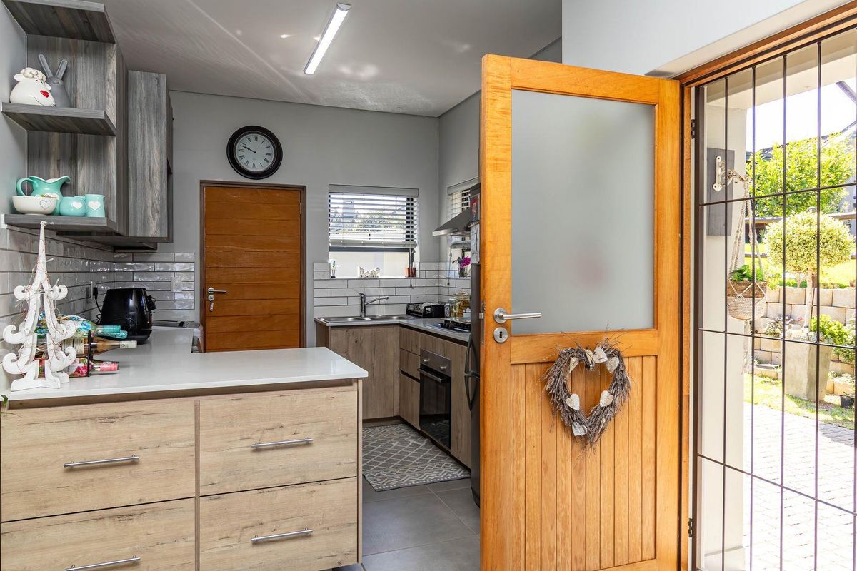 Modern kitchen featuring light wood cabinetry, white countertops, subway tile backsplash, and direct access to the outdoor patio area.