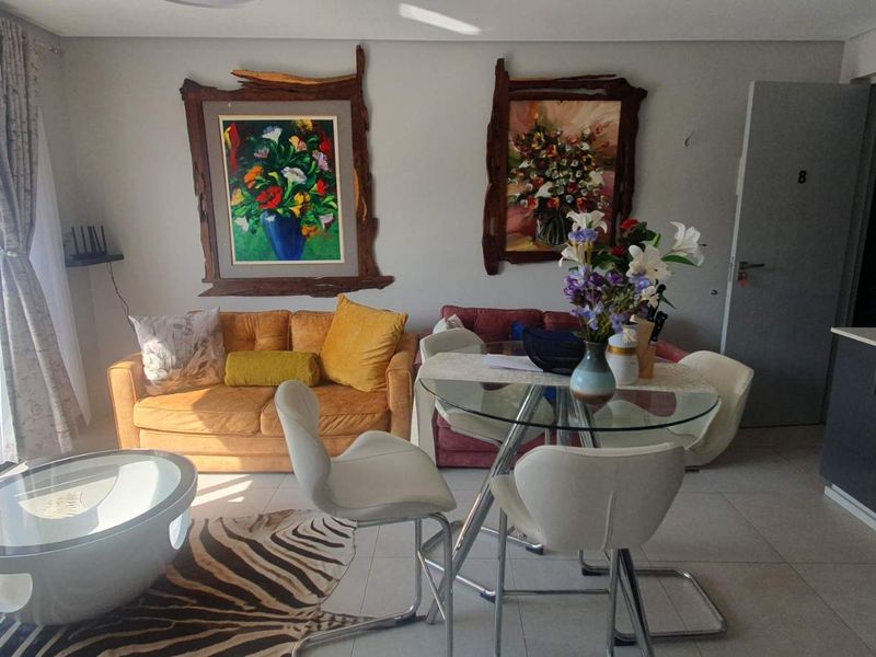 An open-plan living and dining area featuring tiled floors, a modern kitchen with built-in appliances, and large sliding doors leading to an outdoor space.