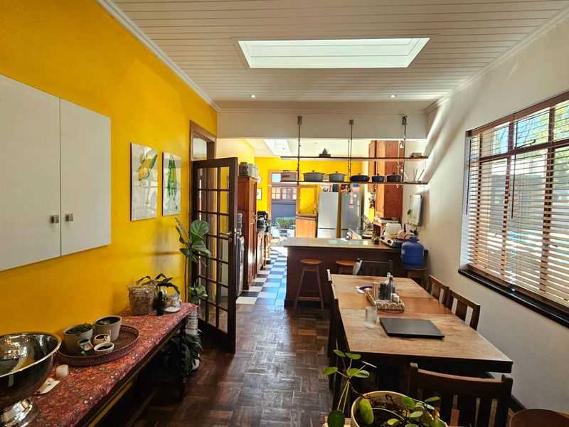 Open-plan dining and kitchen area featuring timber parquet flooring, a central island, and a skylight providing natural light.