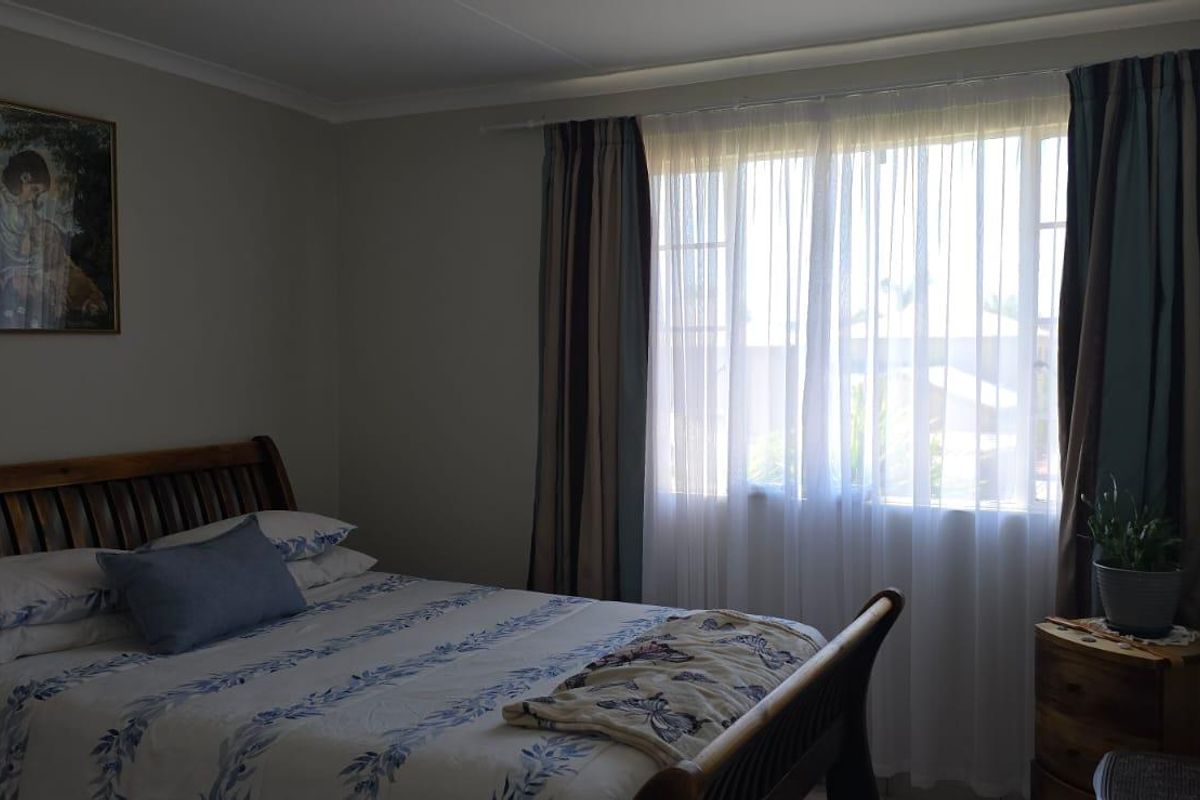 A well-maintained bedroom featuring neutral wall tones, natural light through a window, and classic architectural finishes.