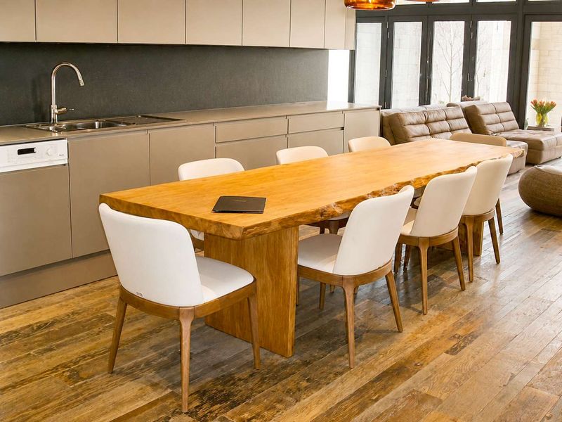 Modern open-plan living area featuring sleek integrated kitchen cabinetry, hardwood flooring, and large bi-fold doors providing seamless access to the outdoors.