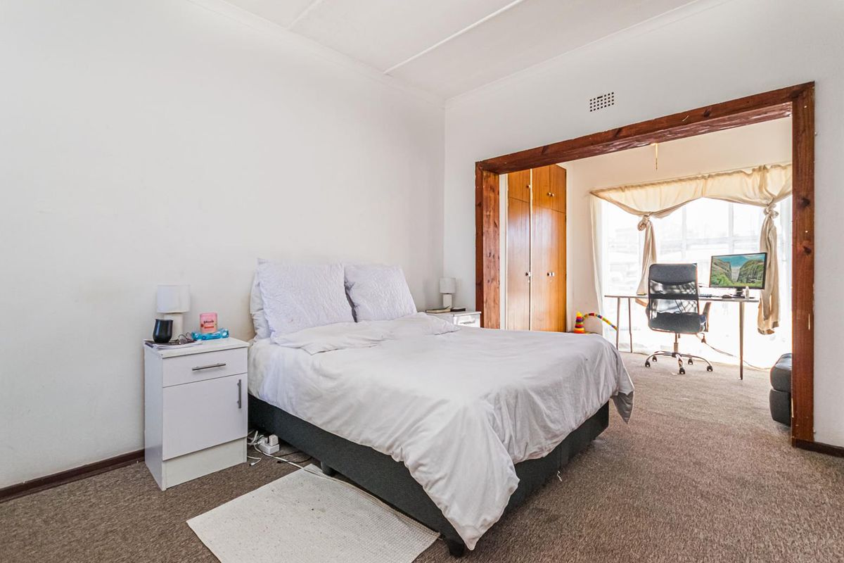 A bedroom featuring carpeted flooring and an adjoining study area with built-in wooden cabinetry.