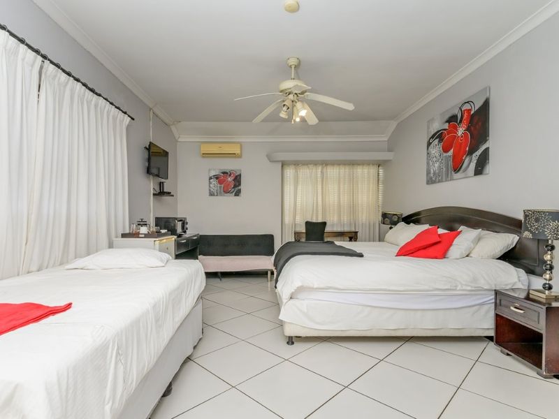 Spacious bedroom featuring tiled flooring, a ceiling fan, and a wall-mounted air conditioning unit.