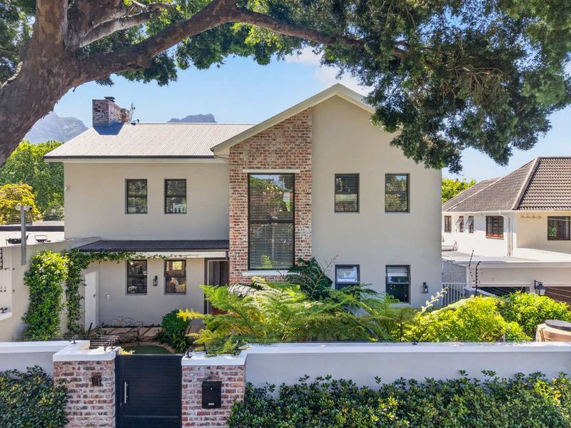 A well-maintained two-story house featuring a brick-accented facade, metal roofing, and a secure gated entrance with perimeter electric fencing.