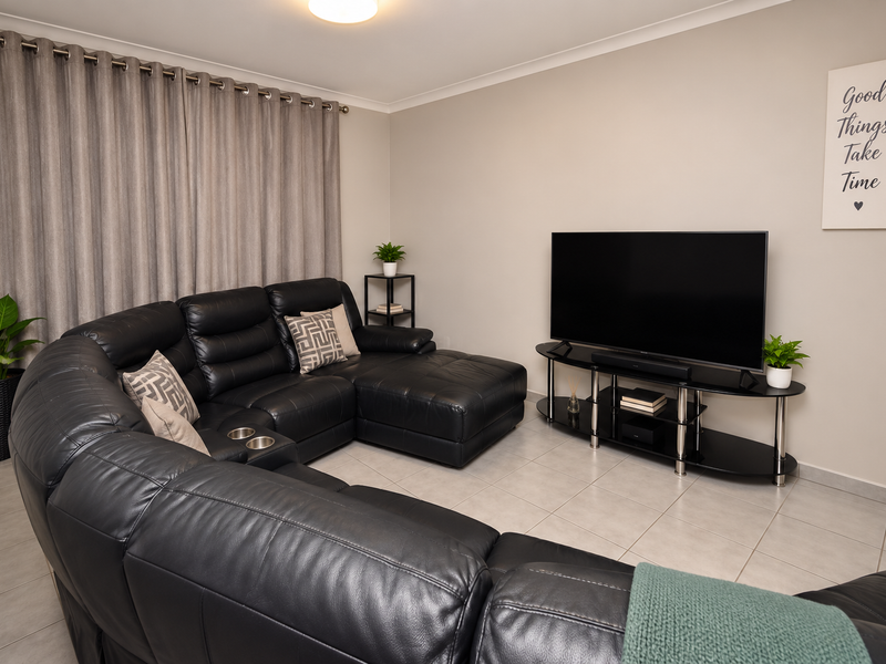 A well-maintained living room featuring neutral tiled flooring and clean wall finishes, providing a comfortable and functional space.