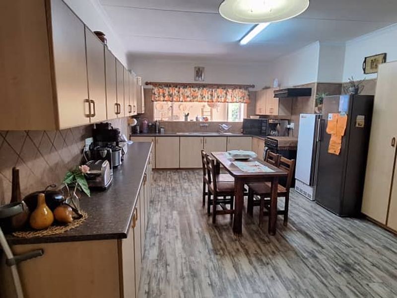 Spacious kitchen featuring extensive laminate cabinetry, ample countertop workspace, a double sink, and integrated pantry storage with durable wood-look flooring.
