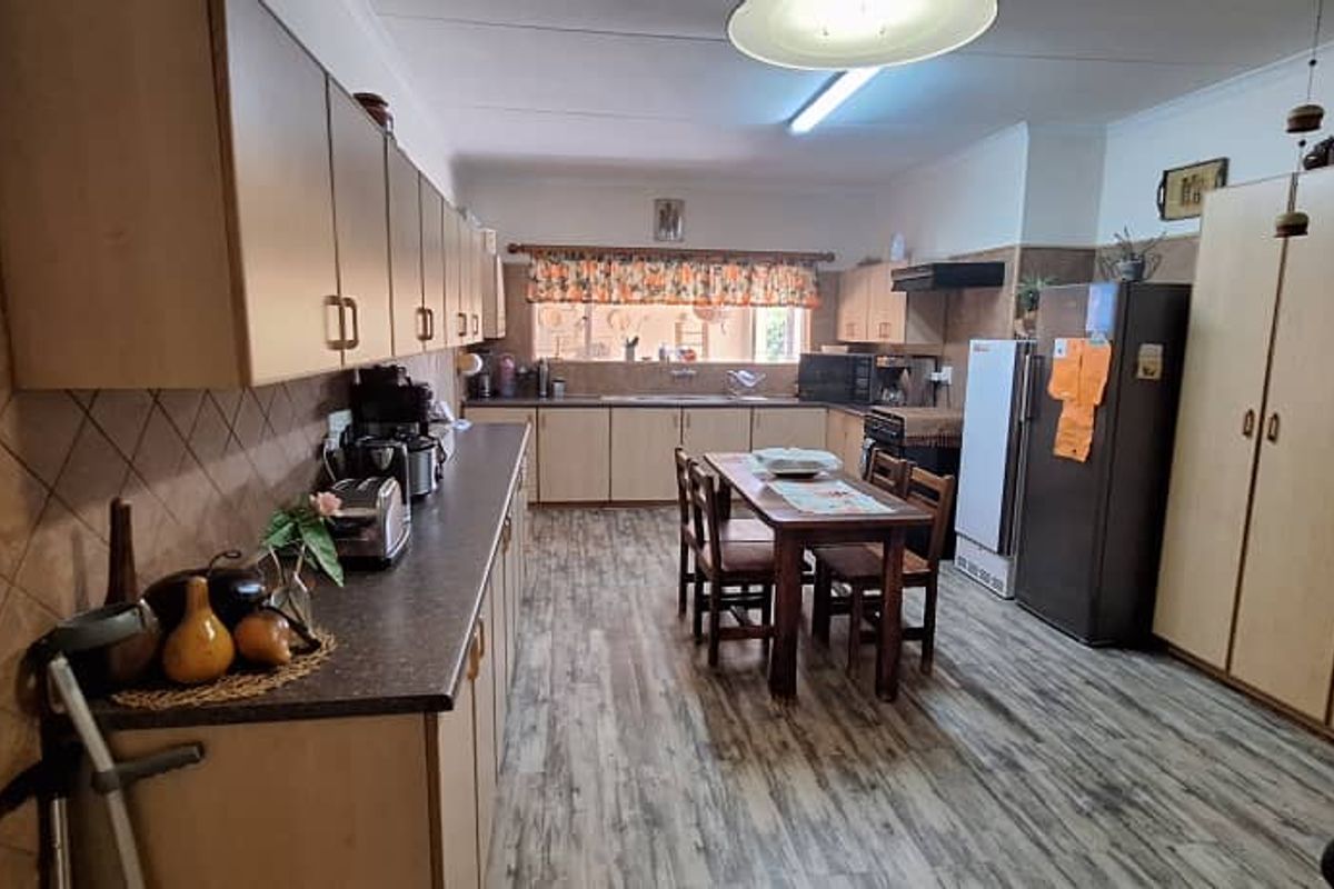 Spacious kitchen featuring extensive laminate cabinetry, ample countertop workspace, a double sink, and integrated pantry storage with durable wood-look flooring.