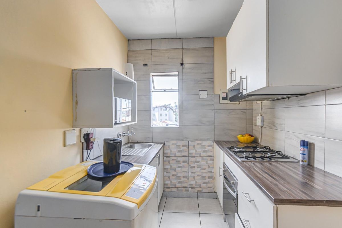 Compact kitchen featuring built-in cabinetry, gas hob, oven, extractor fan, and tiled splashback with a functional layout.
