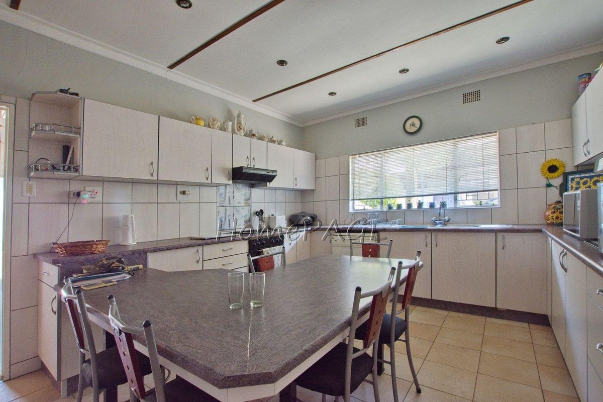 Functional kitchen featuring laminate countertops, built-in cabinetry, integrated stove with extractor fan, and tiled flooring with a central dining area.