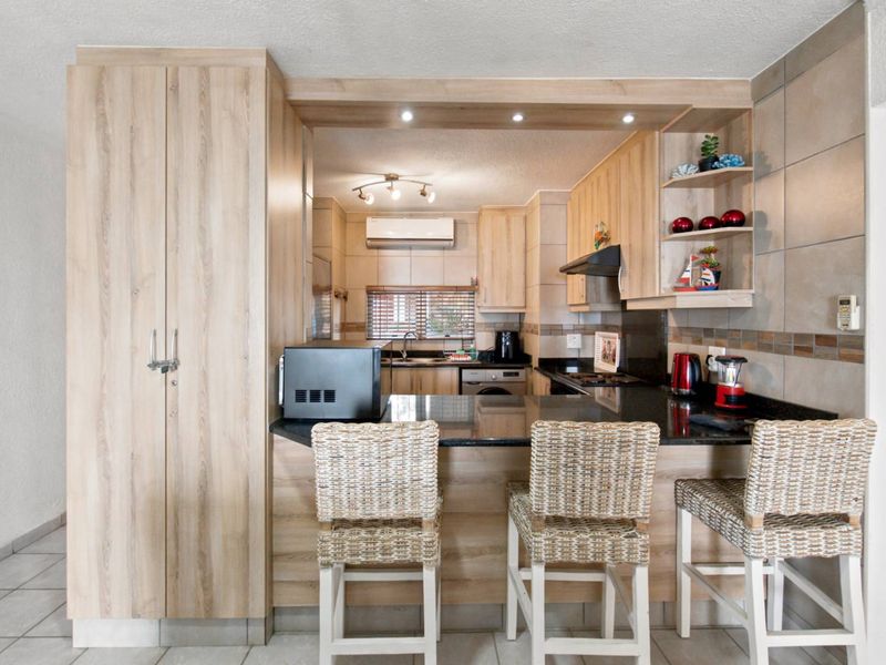 A well-maintained kitchen featuring light wood cabinetry, granite countertops, a breakfast bar, and integrated appliances, offering a functional and modern cooking space.