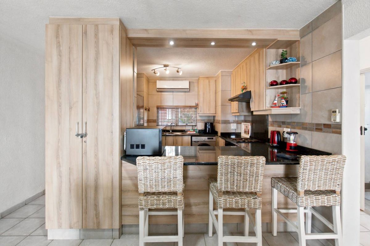 A well-maintained kitchen featuring light wood cabinetry, granite countertops, a breakfast bar, and integrated appliances, offering a functional and modern cooking space.