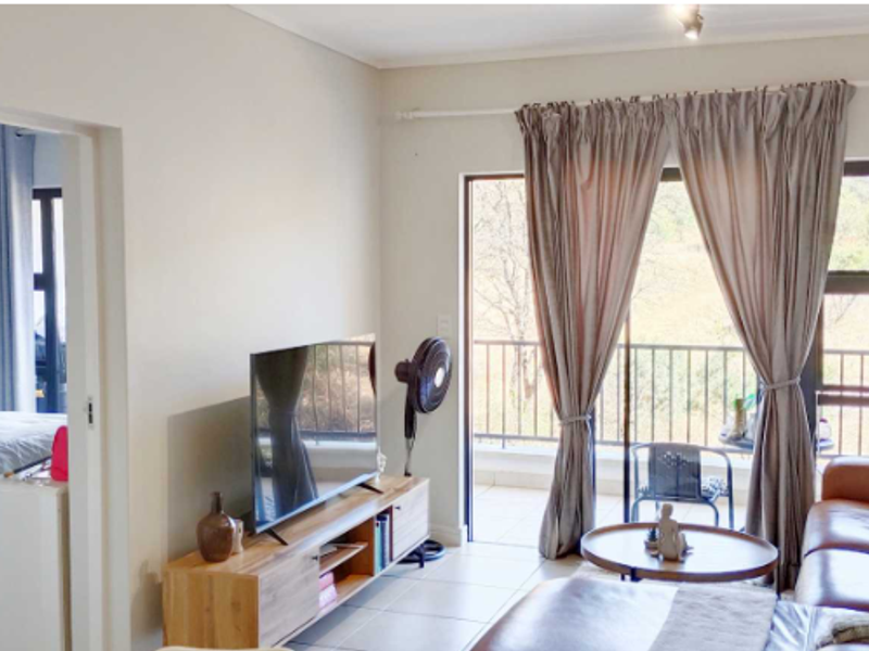 A bright living room featuring tiled flooring and a large sliding glass door that provides direct access to an outdoor balcony.