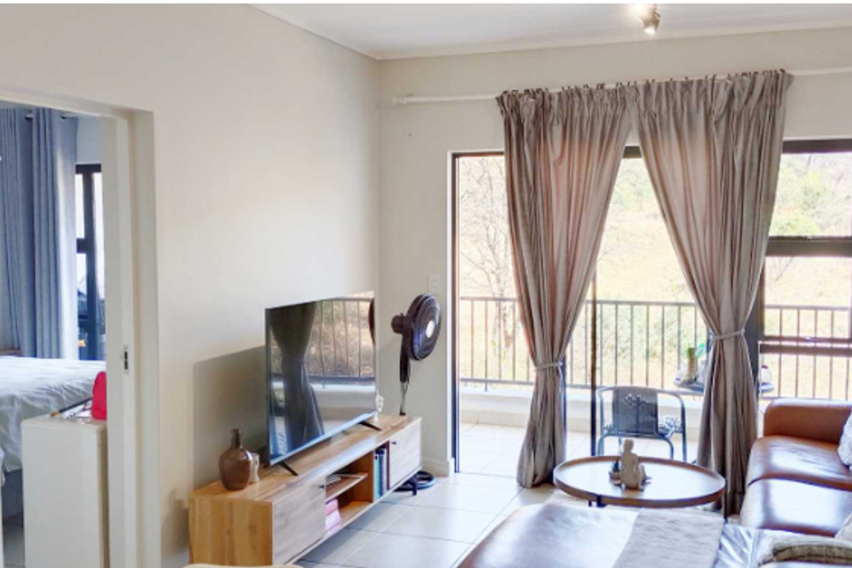 A bright living room featuring tiled flooring and a large sliding glass door that provides direct access to an outdoor balcony.