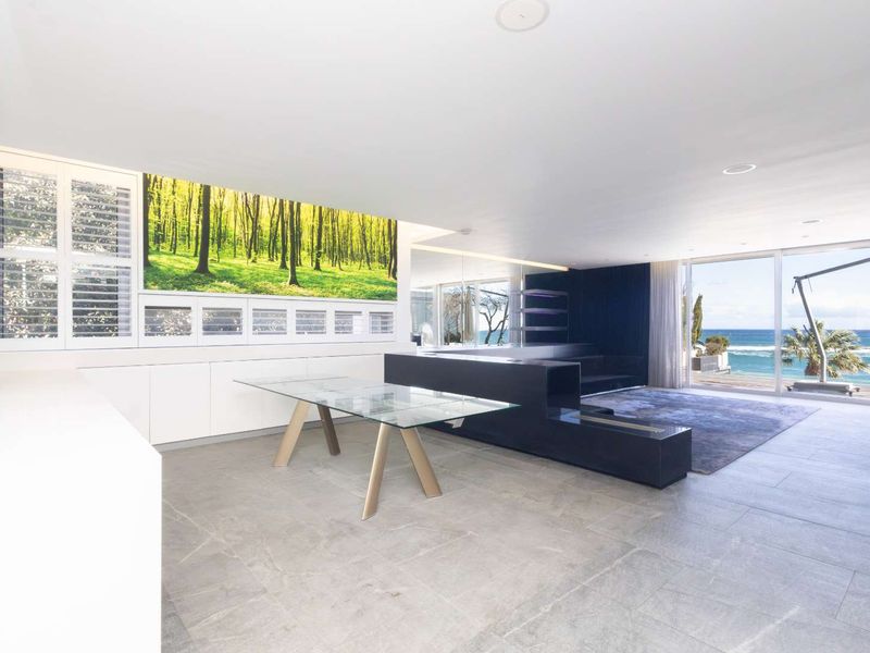 Spacious open-plan living area featuring modern stone tile flooring, built-in cabinetry, and large sliding glass doors offering expansive ocean views.