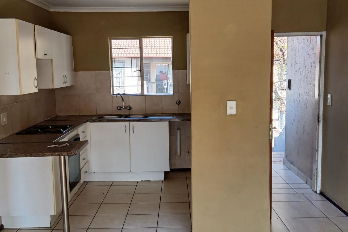 A functional kitchen featuring built-in cabinetry, granite countertops, a built-in hob and oven, and tiled flooring, offering a blank canvas for potential updates.