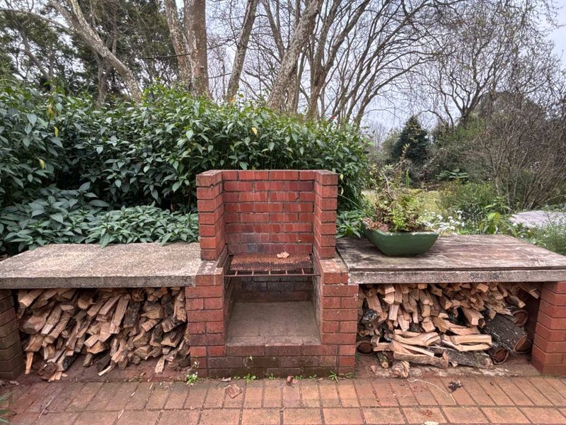 Outdoor patio area featuring a built-in brick braai with integrated concrete countertops and dedicated wood storage compartments.