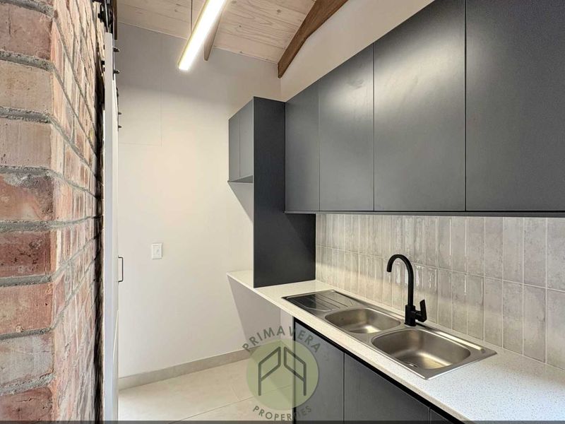 Modern scullery featuring matte grey cabinetry, double stainless steel sink with black faucet, subway tile backsplash, and exposed brick wall with timber ceiling beams.