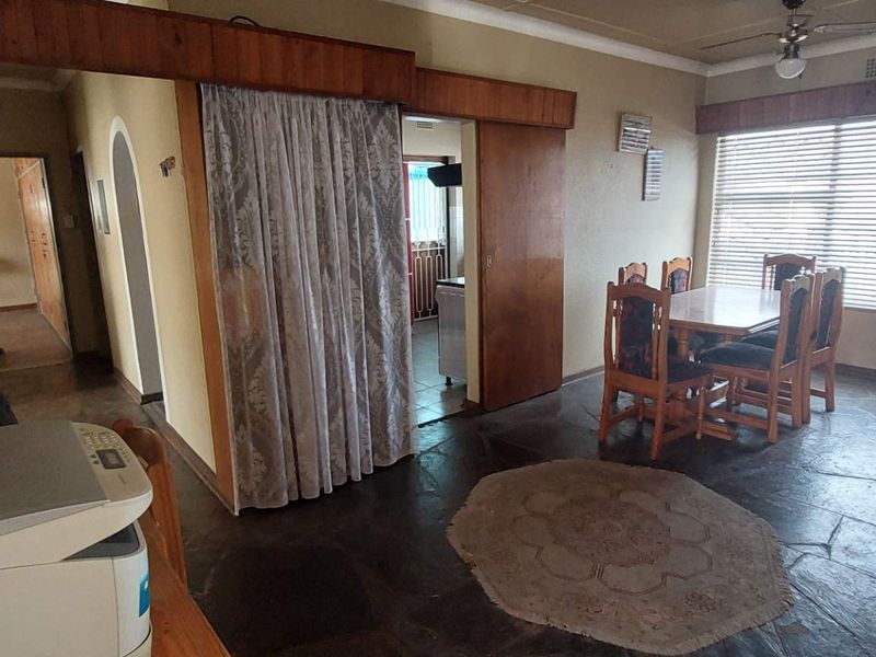 A living area featuring natural stone flooring, a ceiling fan, and a timber-framed sliding door leading to an adjacent space.