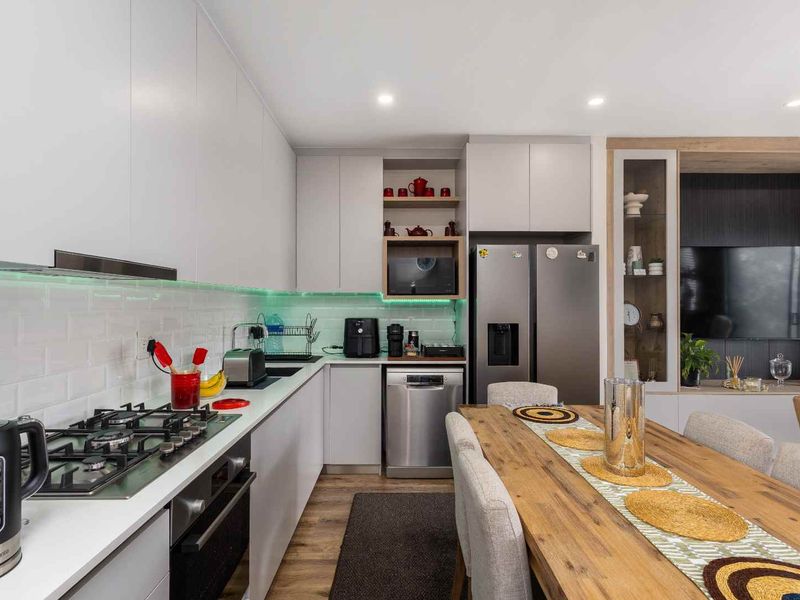 Modern open-plan kitchen featuring sleek cabinetry, subway tile backsplash, gas cooktop, and integrated appliances, seamlessly flowing into the dining and living area.