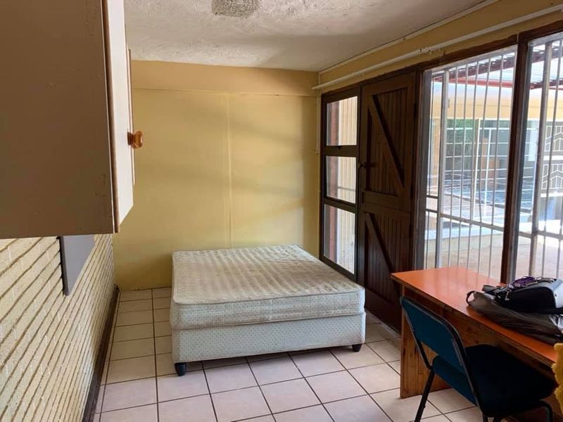 A bedroom featuring tiled flooring, built-in cabinetry, and a sliding glass door providing access to an outdoor area.