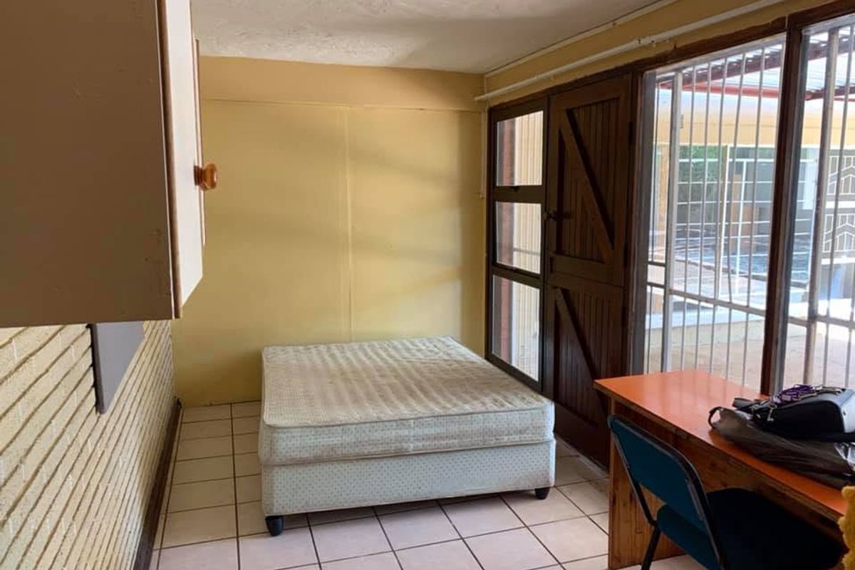 A bedroom featuring tiled flooring, built-in cabinetry, and a sliding glass door providing access to an outdoor area.