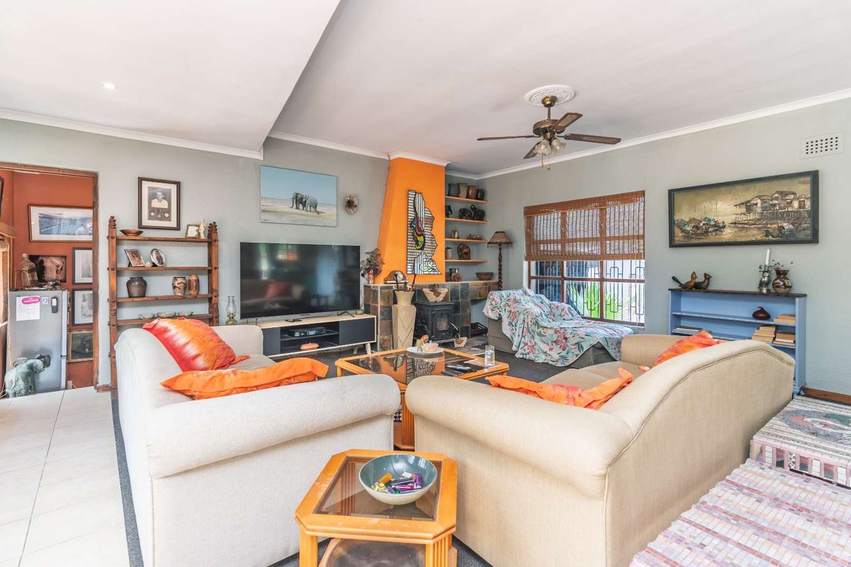 A comfortable living room featuring a fireplace, built-in shelving, and a ceiling fan, offering a functional and lived-in space.