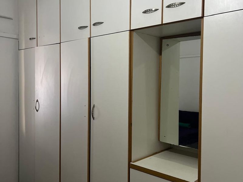 A bedroom featuring floor-to-ceiling built-in cupboards with an integrated vanity unit and mirror, providing ample storage space.