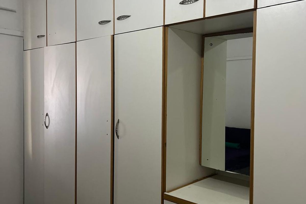 A bedroom featuring floor-to-ceiling built-in cupboards with an integrated vanity unit and mirror, providing ample storage space.