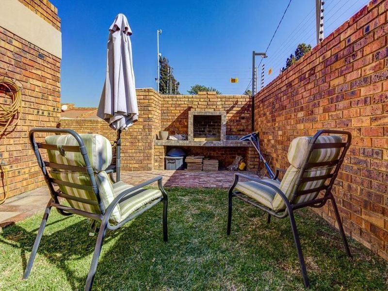 Private outdoor patio area featuring a built-in brick braai, enclosed by high brick boundary walls with integrated electric fencing for added security.