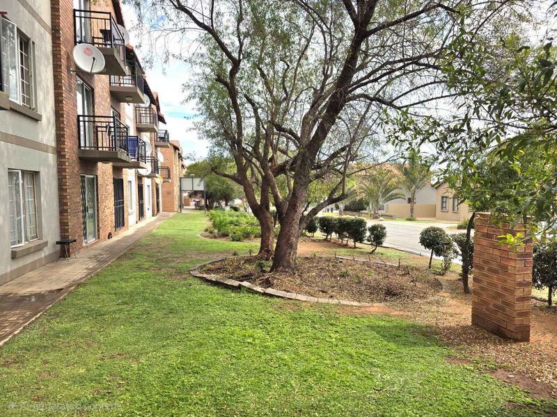 A view of the apartment complex exterior featuring a landscaped garden, paved walkways, and private balconies on the building facade.