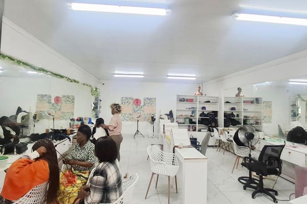A functional commercial workspace featuring large wall-mounted mirrors, built-in storage shelving, and bright overhead fluorescent lighting, suitable for a salon or studio environment.