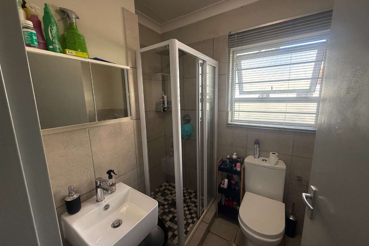 A functional bathroom featuring a shower enclosure, wall-mounted basin, toilet, and tiled finishes, providing a practical and compact layout.
