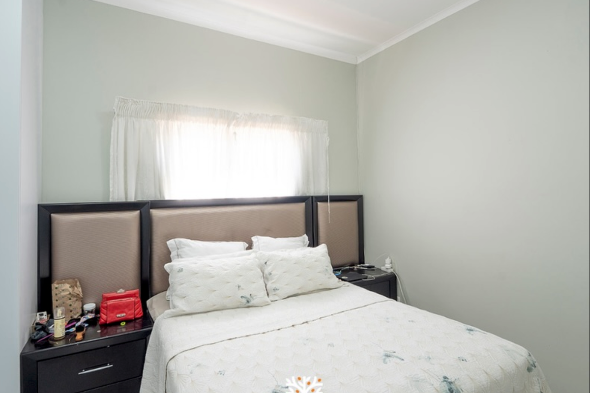 A standard bedroom featuring neutral wall paint, cove cornicing, and a window with fitted curtain tracks.
