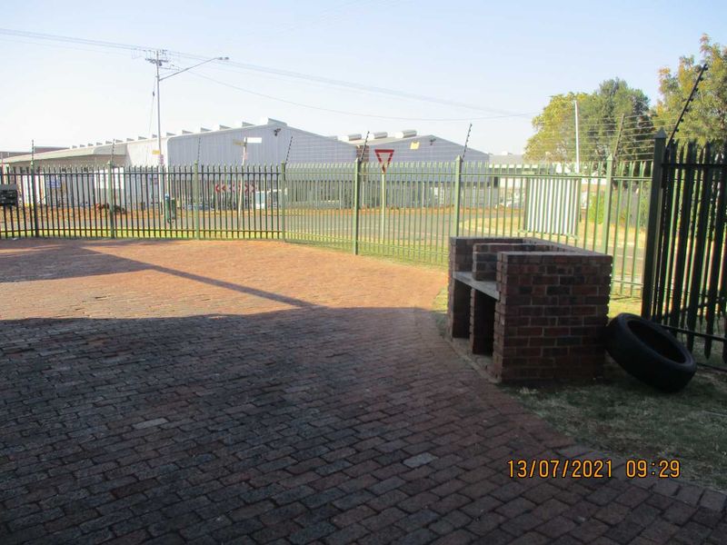 Outdoor area featuring brick paving and a built-in brick braai, enclosed by steel perimeter fencing with electric security wires.